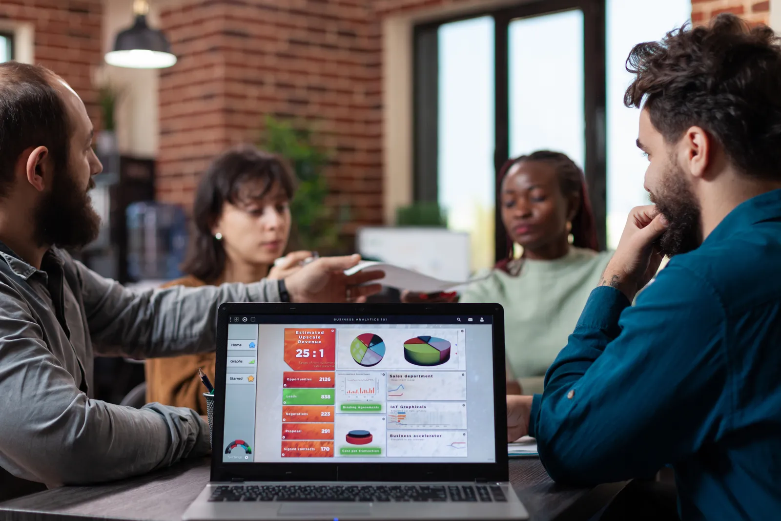 Freemium SaaS team reviewing free-to-paid conversion and usage dashboards together on a laptop in their office