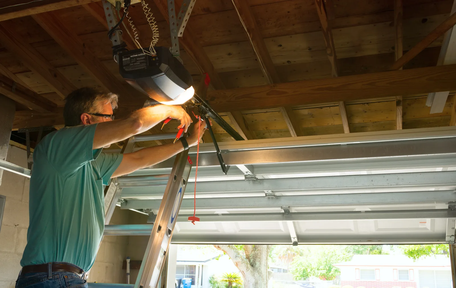 Garage door technician repairing an overhead opener inside a residential garage
