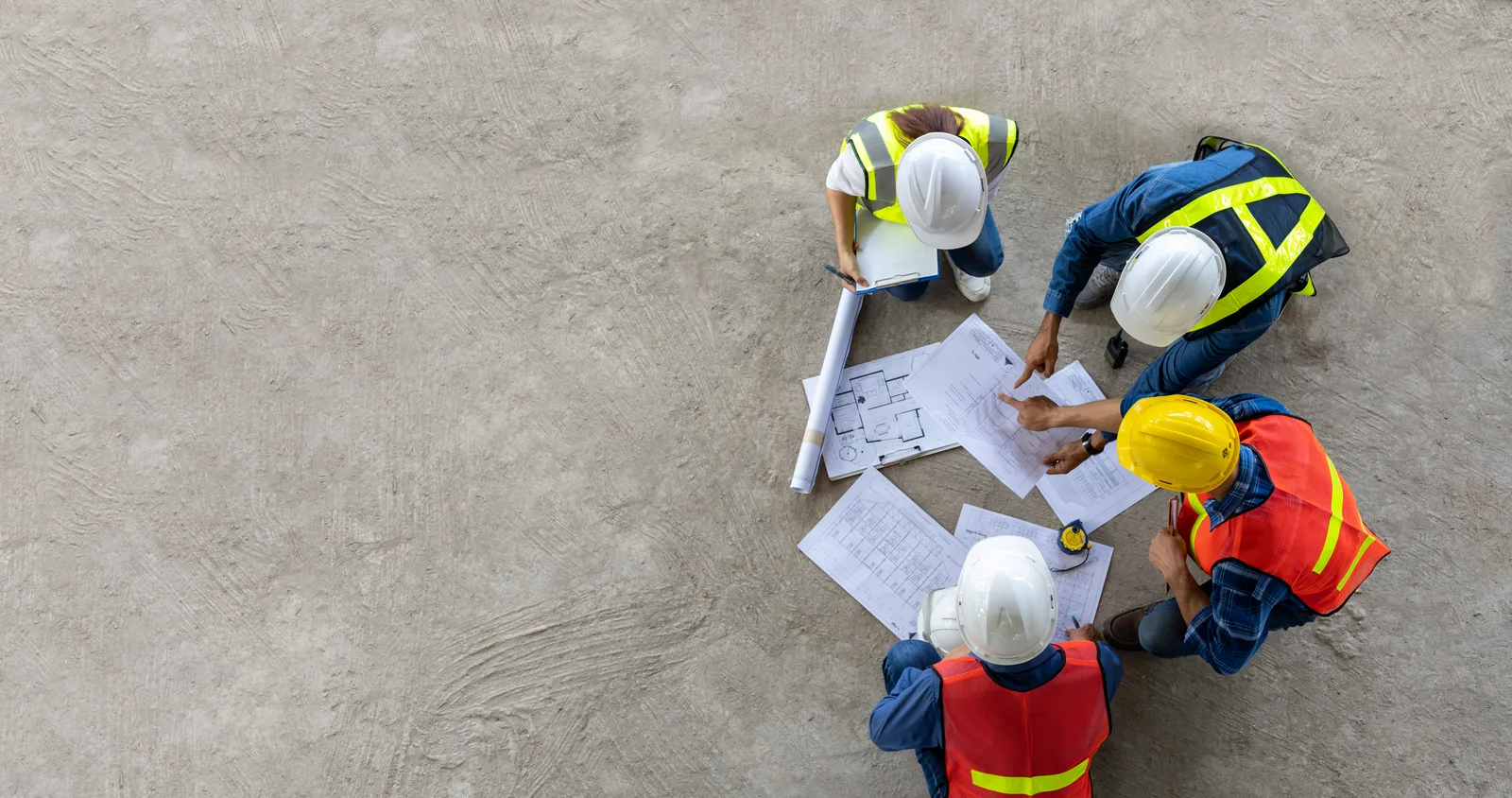 A general contractor in a hard hat reviewing blueprints with a homeowner at a home addition job site