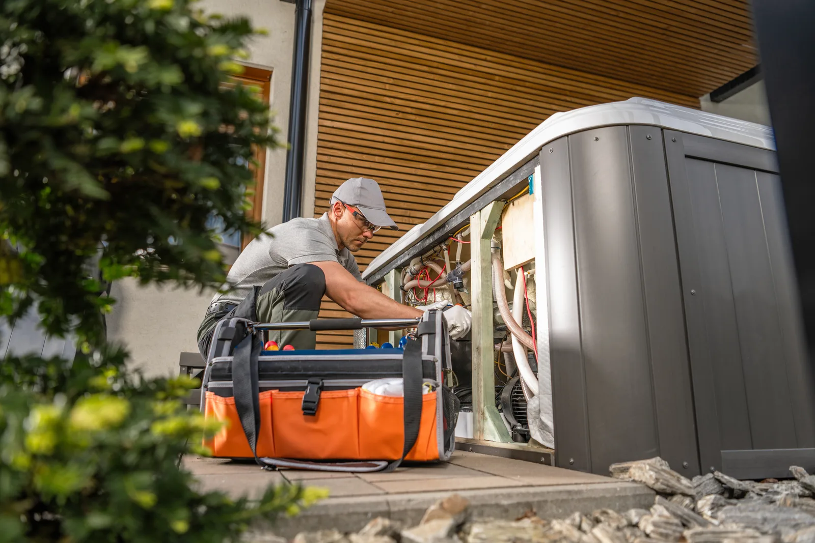 Technician checking the control panel of a whole-home standby generator during a maintenance visit outside a house