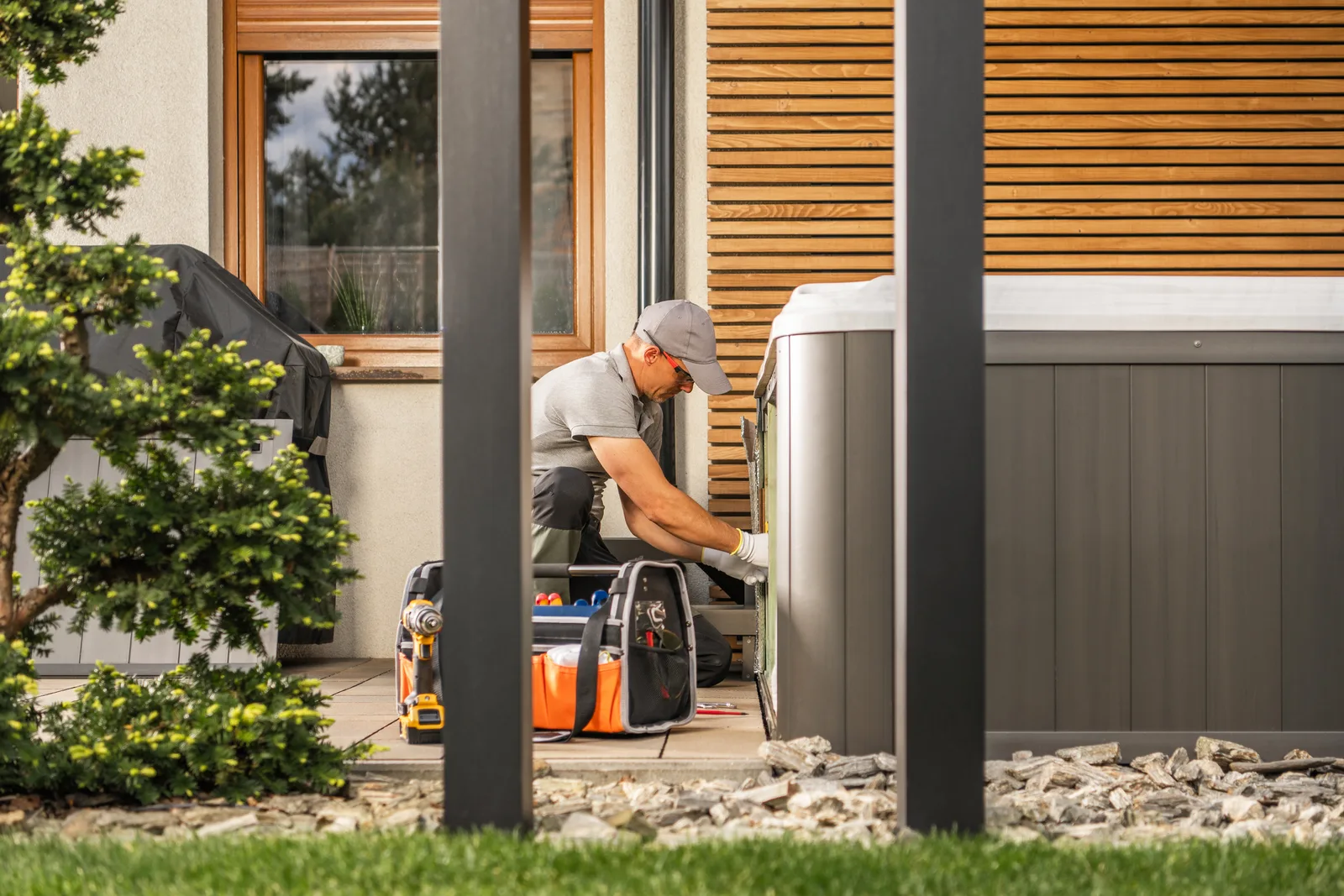 Technician bolting a whole-home standby generator to its concrete pad outside a suburban house