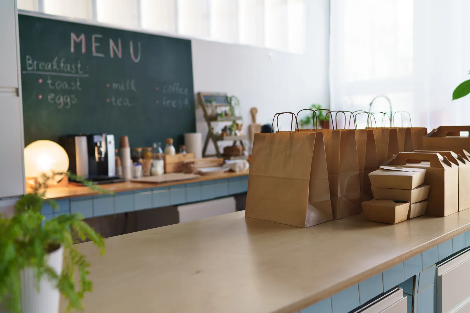 Packed takeout delivery bags lined up on the counter of a ghost kitchen