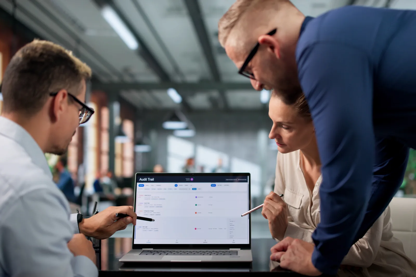 GRC software team reviewing a compliance dashboard together on a laptop in a modern office
