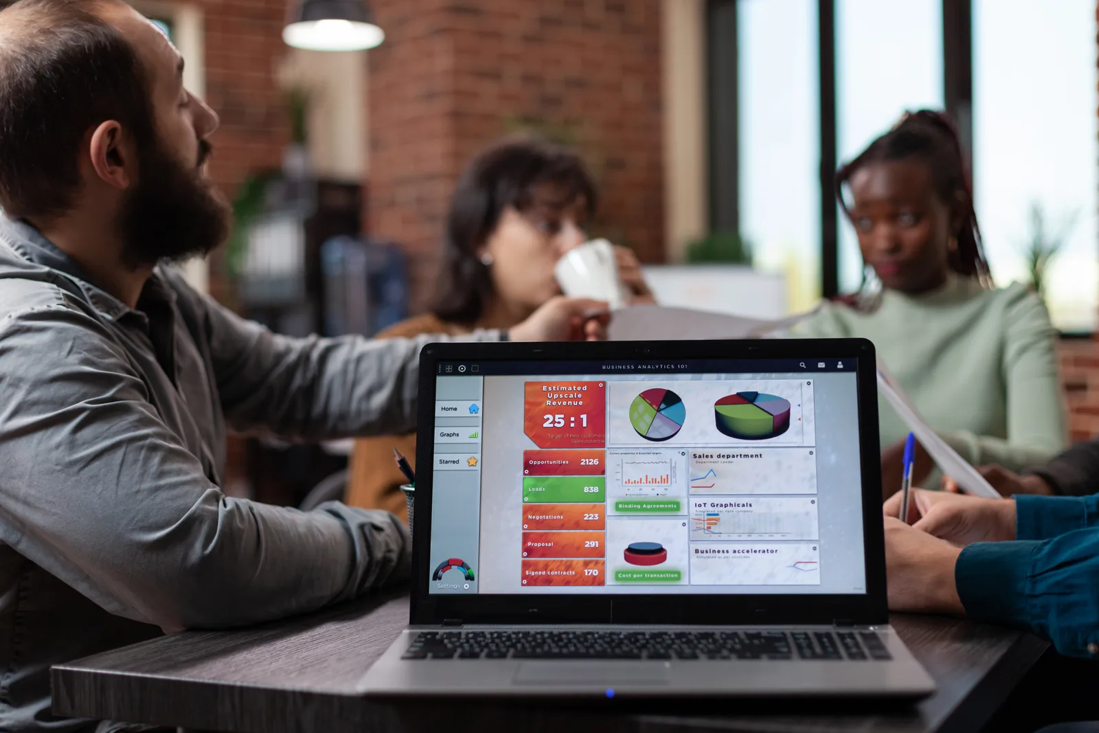 SaaS revenue and marketing team reviewing pipeline and expansion-revenue dashboards together at a laptop in a modern office