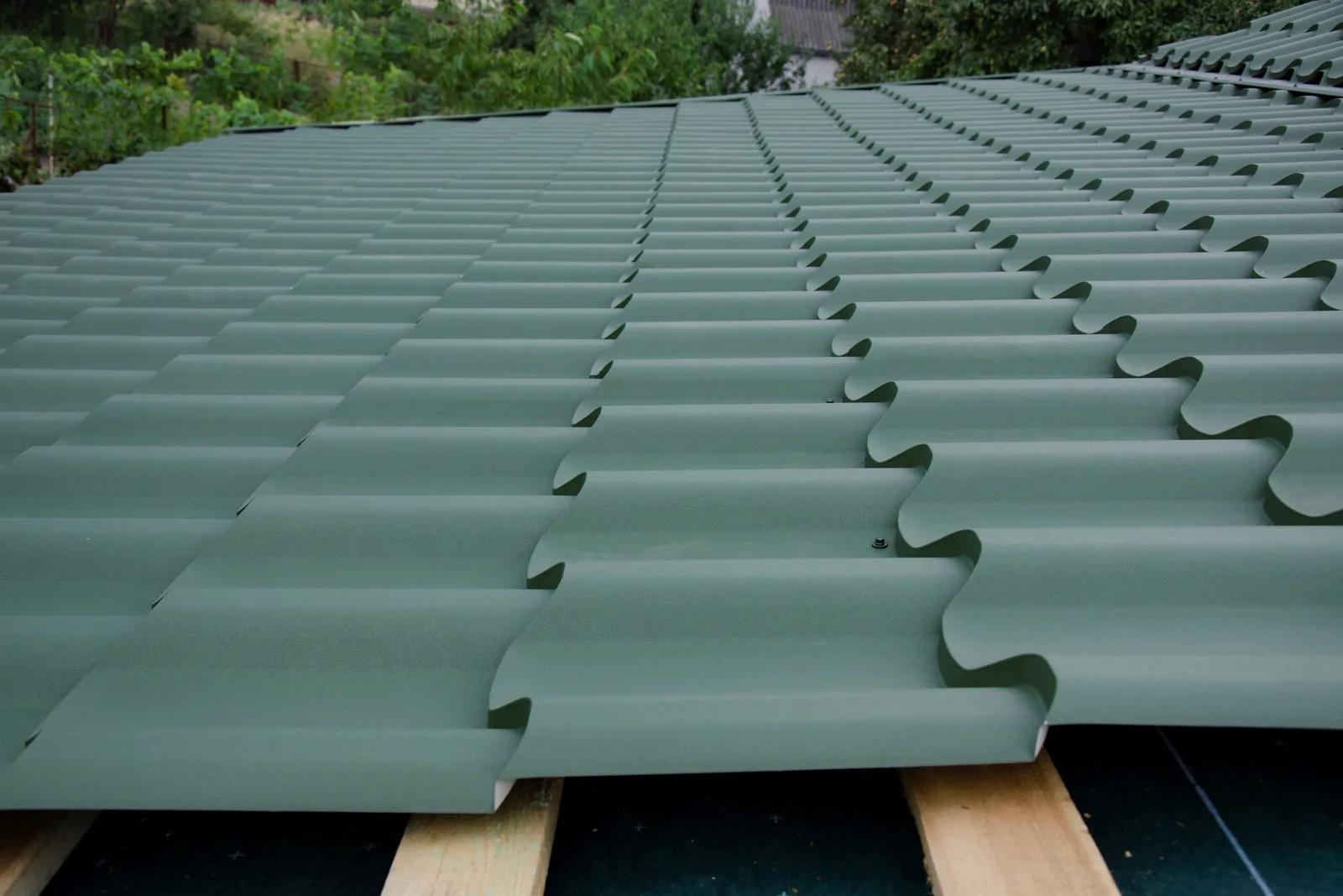 An installer on a ladder fastening a new seamless aluminum gutter along the roofline of a suburban home
