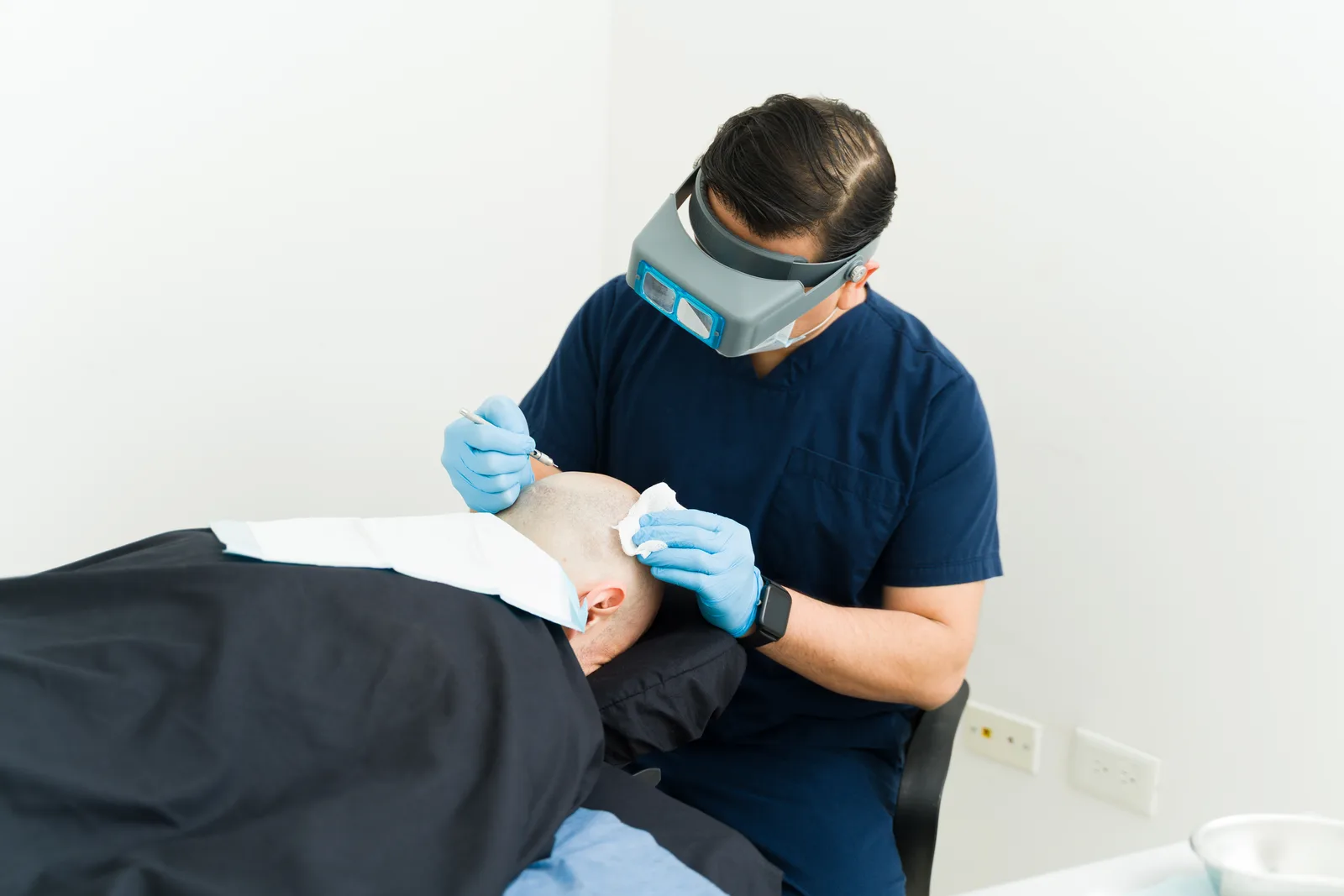 Surgeon placing hair grafts along a patient's hairline during an FUE procedure