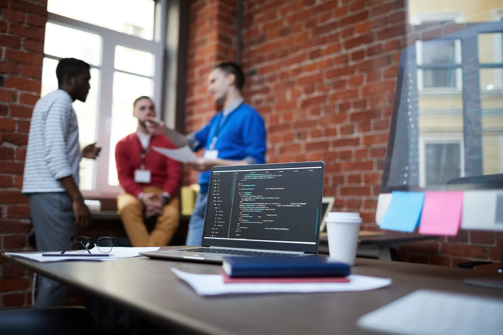 Laptop showing storefront code on a table in a team's open office