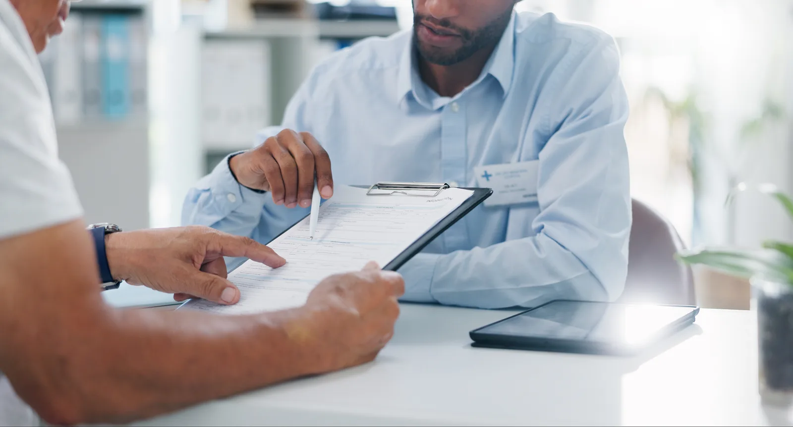 A health insurance broker reviewing Medicare Advantage plan options with a client at a desk