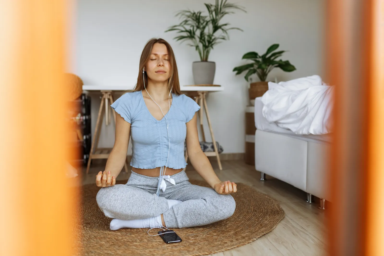 Woman meditating at home with her phone beside her, using a meditation app