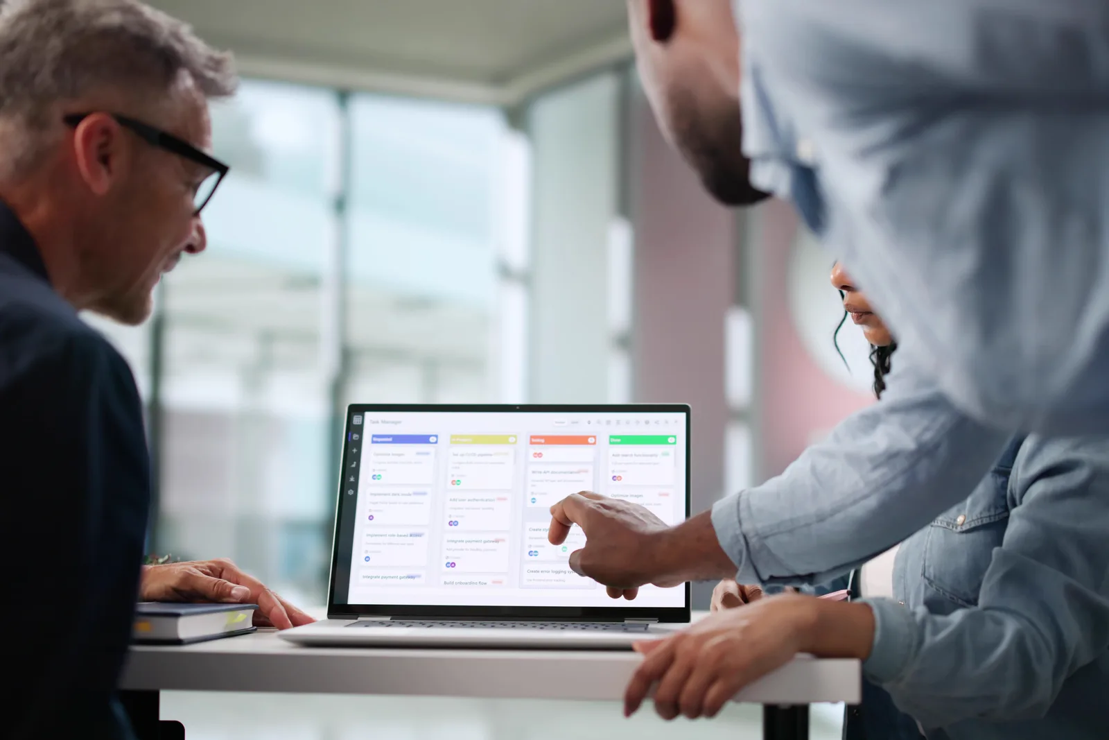 Home care software product team reviewing caregiver scheduling and visit-verification dashboards together on a laptop in their office