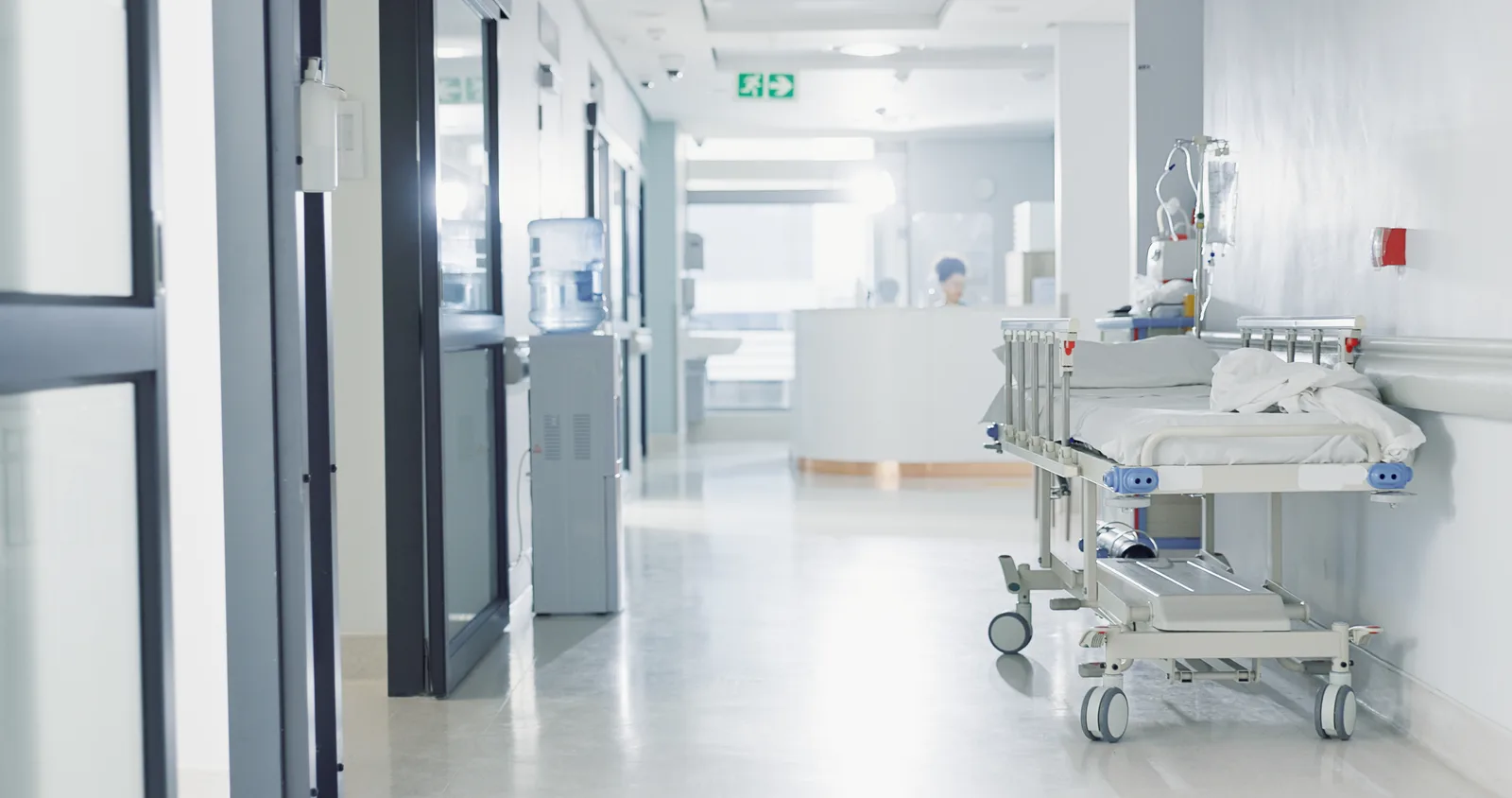 A hospital care team consulting at a nurses' station in a busy hospital corridor