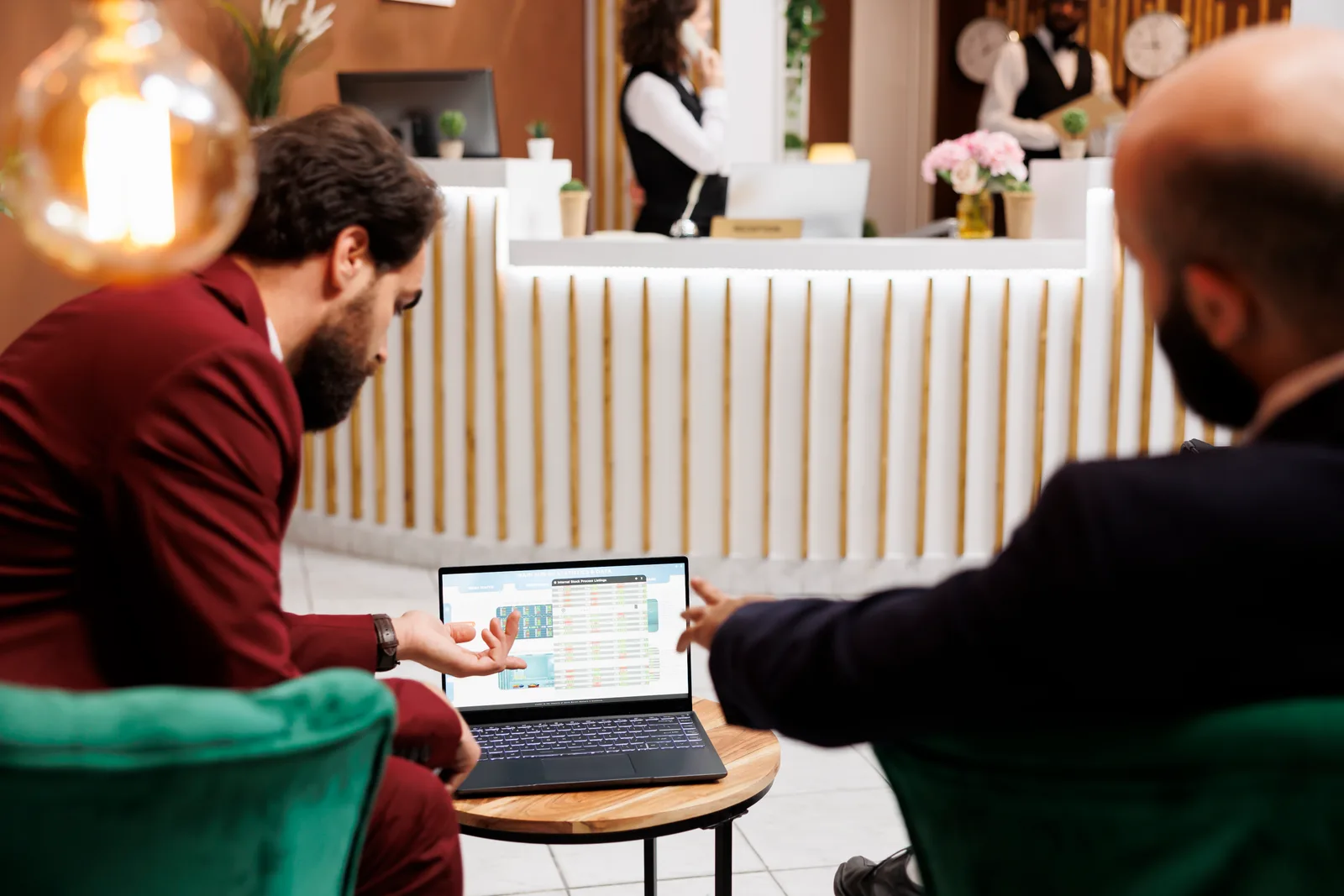 Hotel software team reviewing a front-desk and reservations dashboard together at a laptop in their office