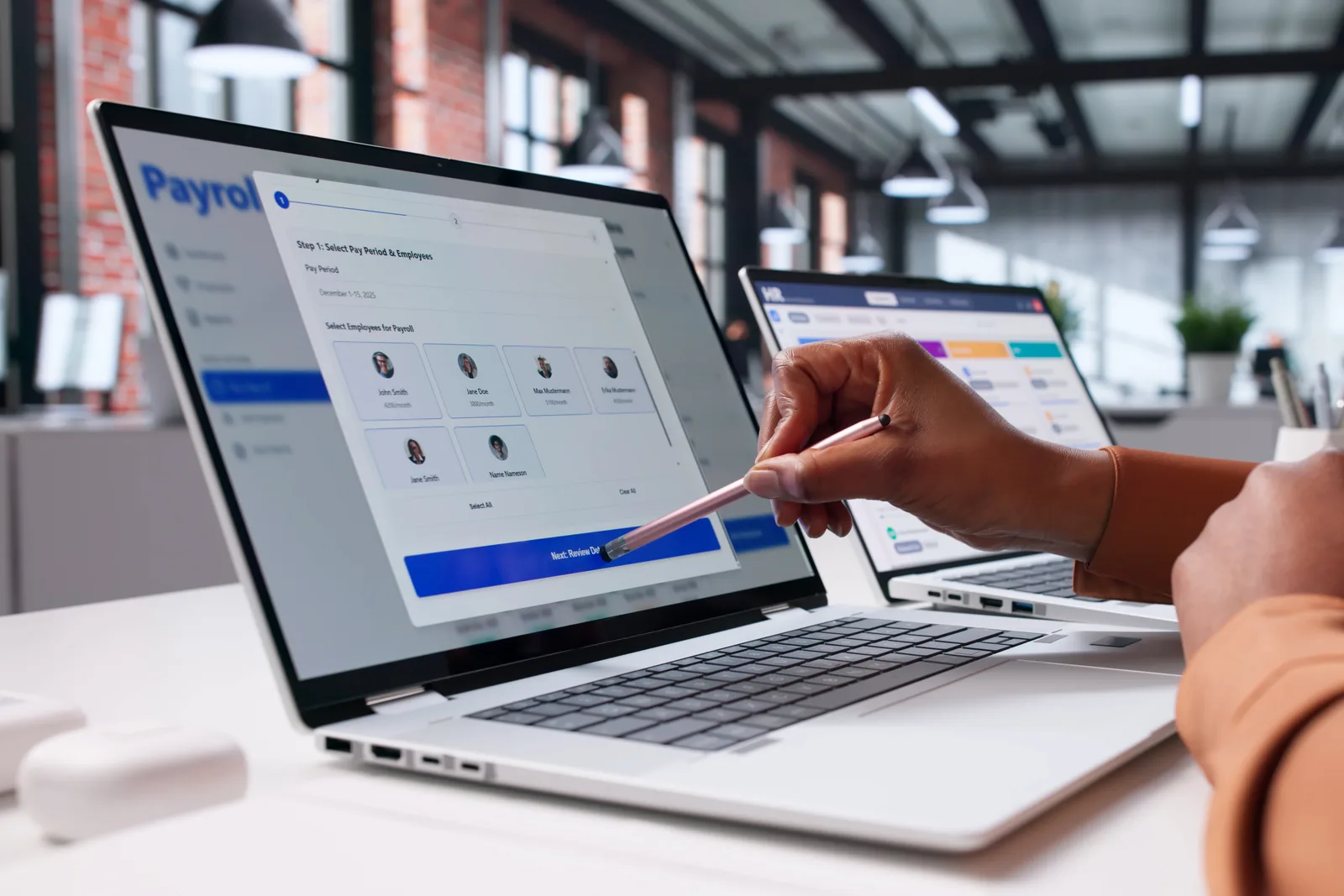 HRIS product team reviewing employee onboarding and payroll dashboards together on a laptop in their office