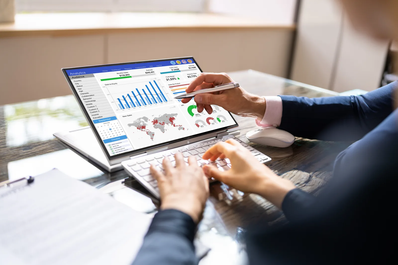 HR technology team reviewing a workforce management and payroll dashboard together on a laptop in their office