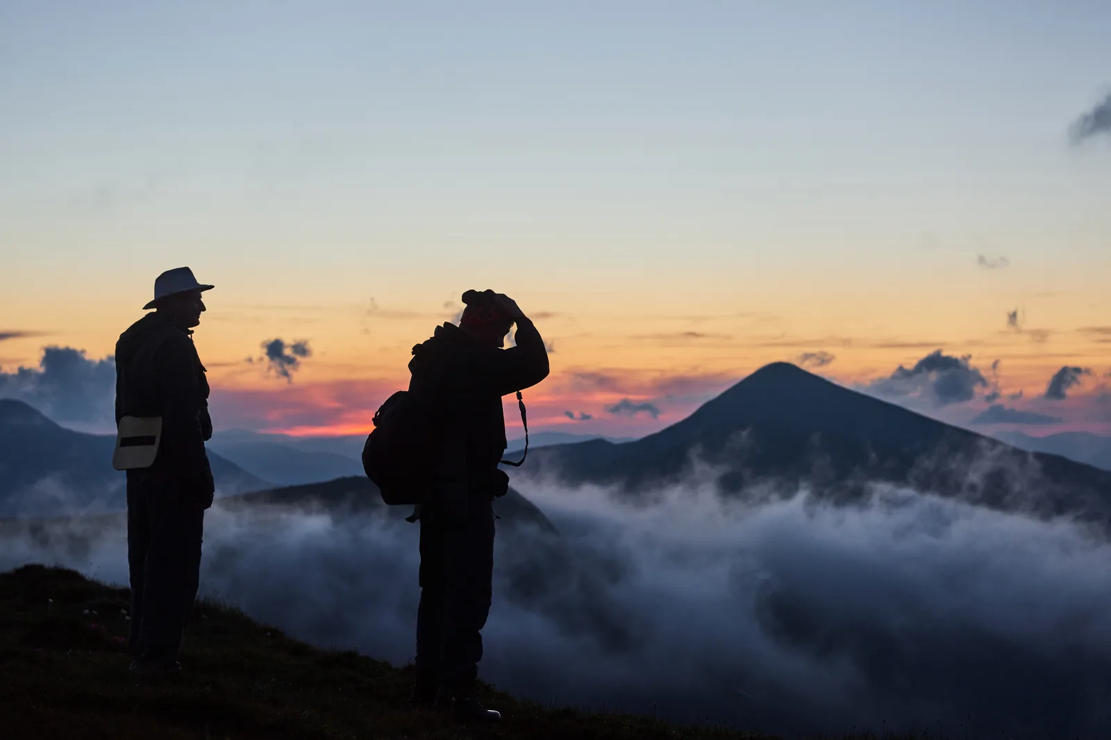 Hunting guide and client glassing a ridge with binoculars for game during a guided hunt at sunrise