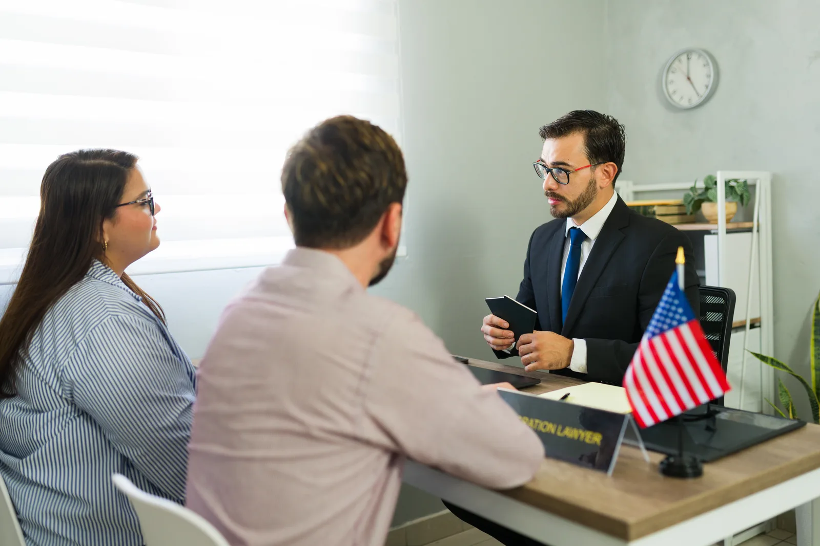 Immigration attorney reviewing green card paperwork with a young couple in her office
