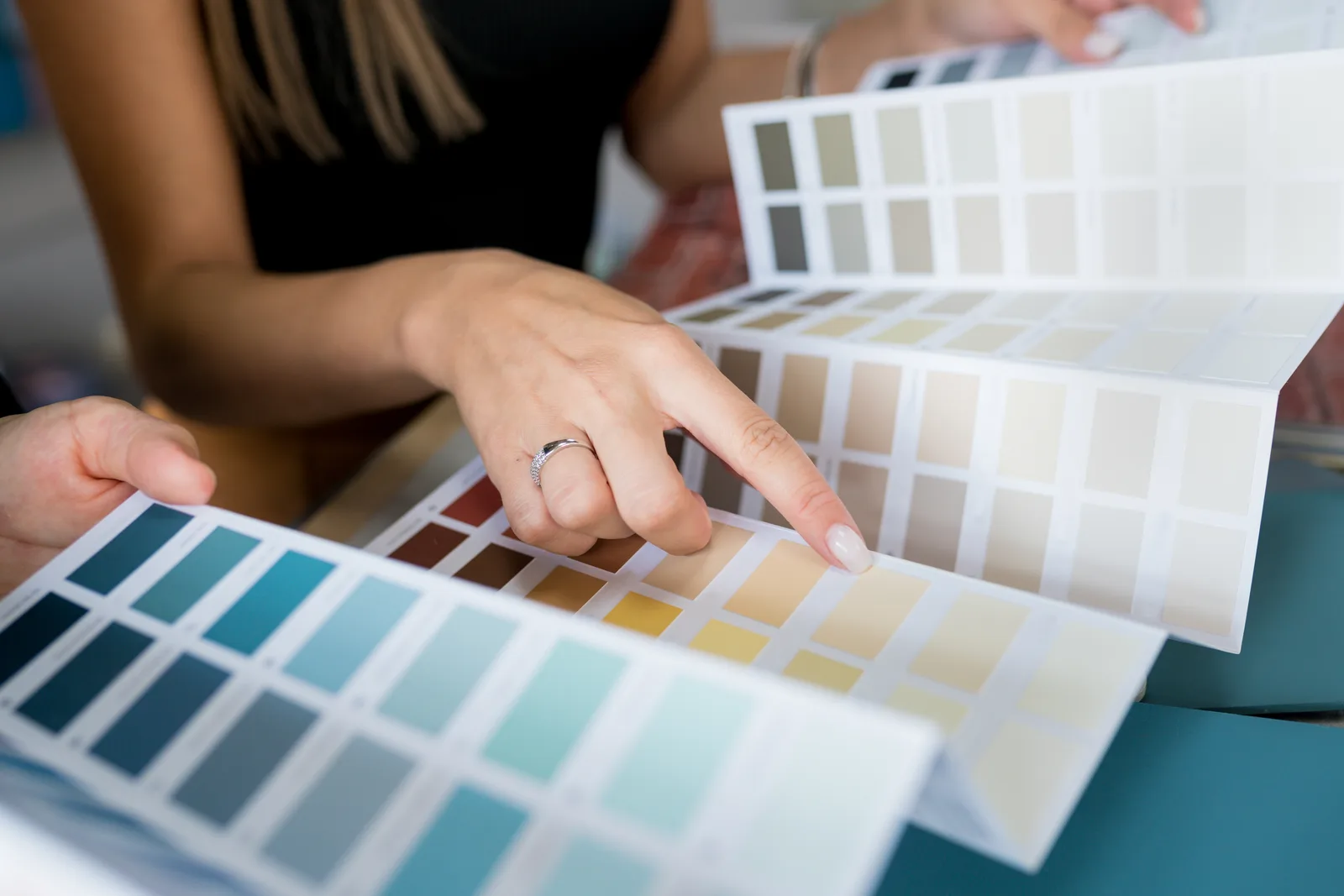 Interior designer comparing fabric and paint swatches over a floor plan in a bright, styled living room