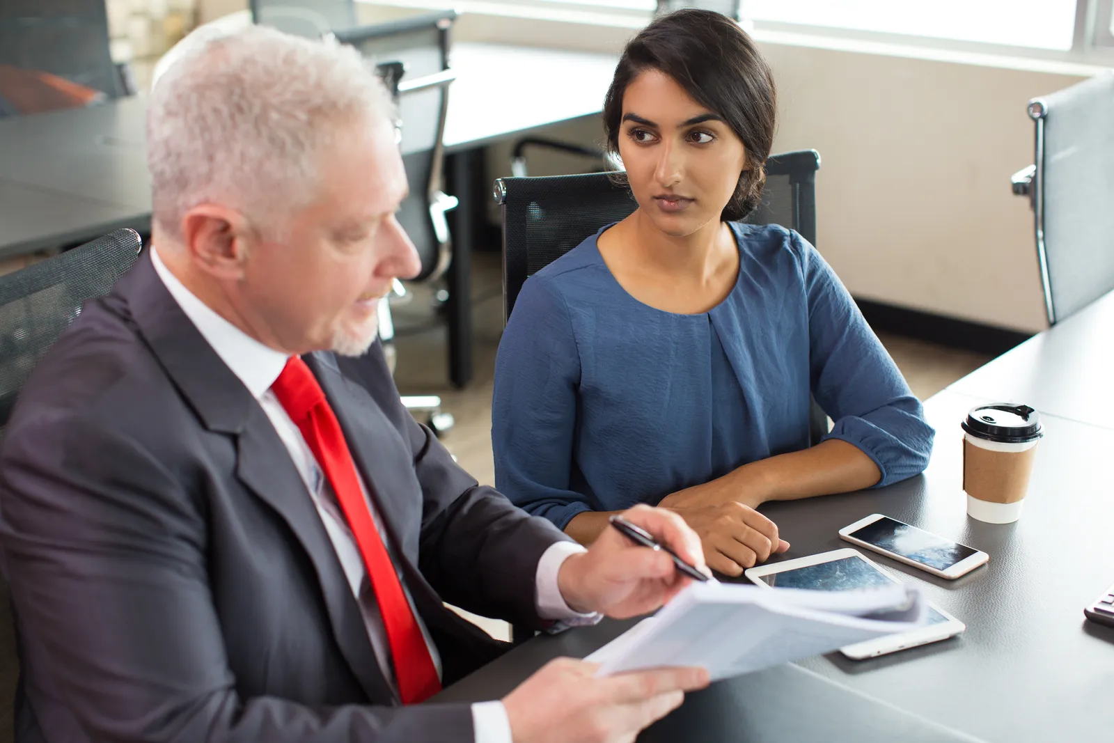 International trade attorney reviewing an export license application and customs paperwork with a client at a conference table