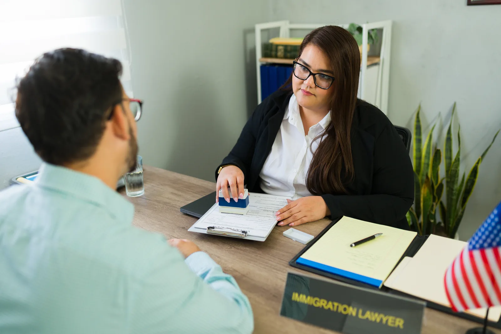 Immigration attorney reviewing EB-5 investment and source-of-funds documents with a client across a conference table