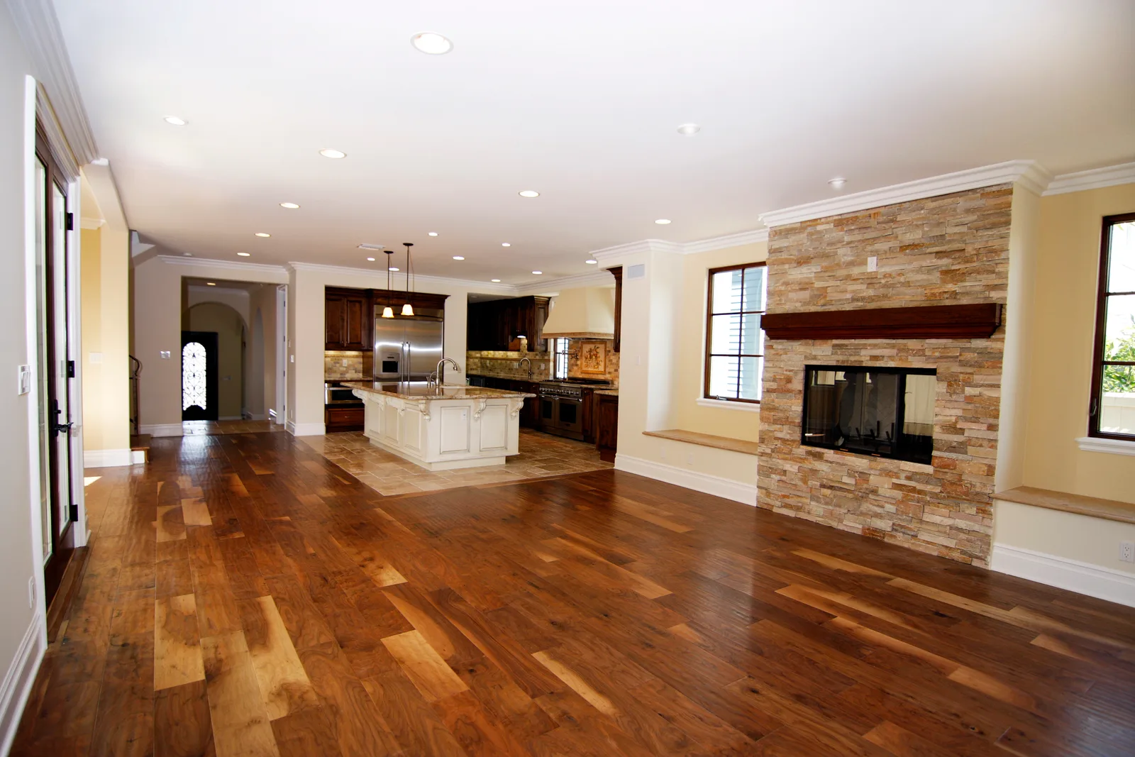 Open-plan remodeled kitchen with a cream island, dark wood cabinets, and new hardwood floors