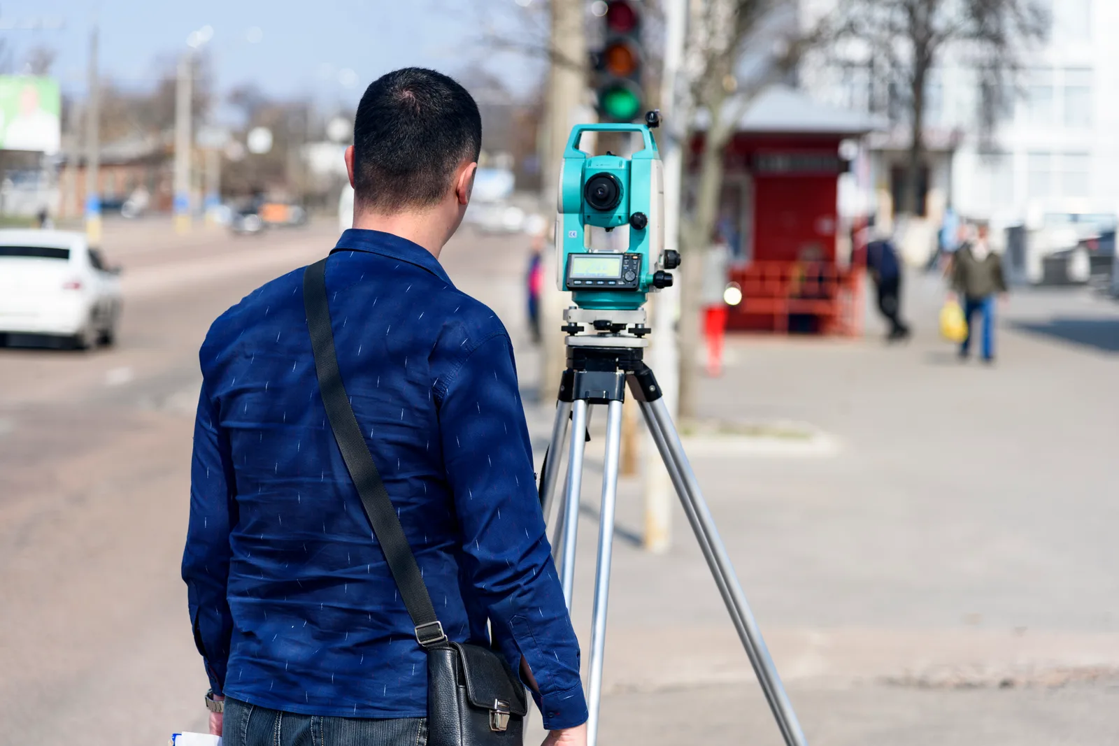 Land surveyor sighting through a total station on a tripod at a residential property boundary
