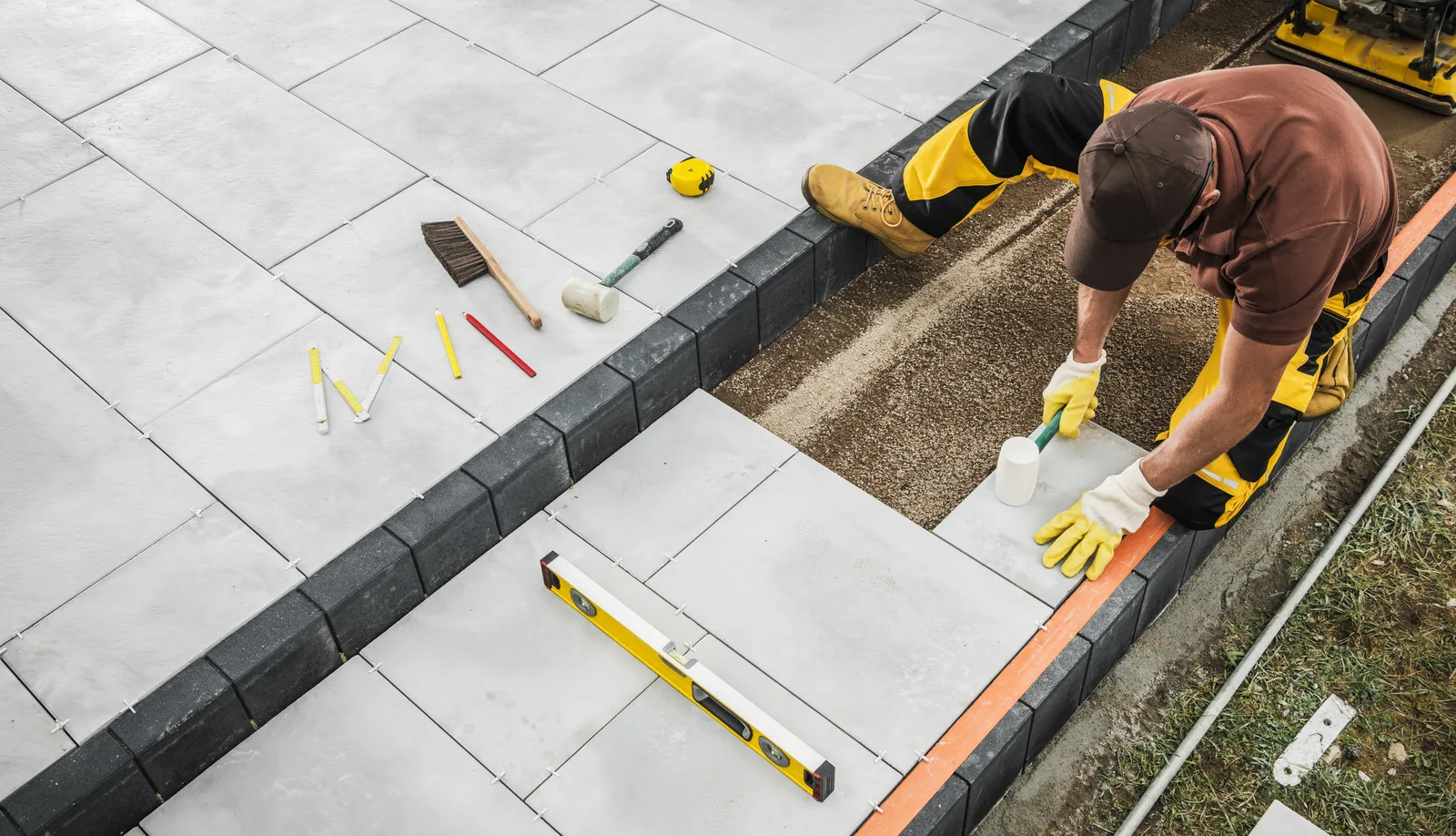 Landscaper setting paver stones for a new backyard patio at a client's home