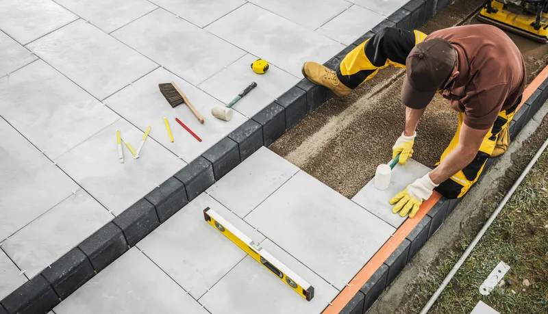 Landscaping contractor installing a paver patio in a residential backyard