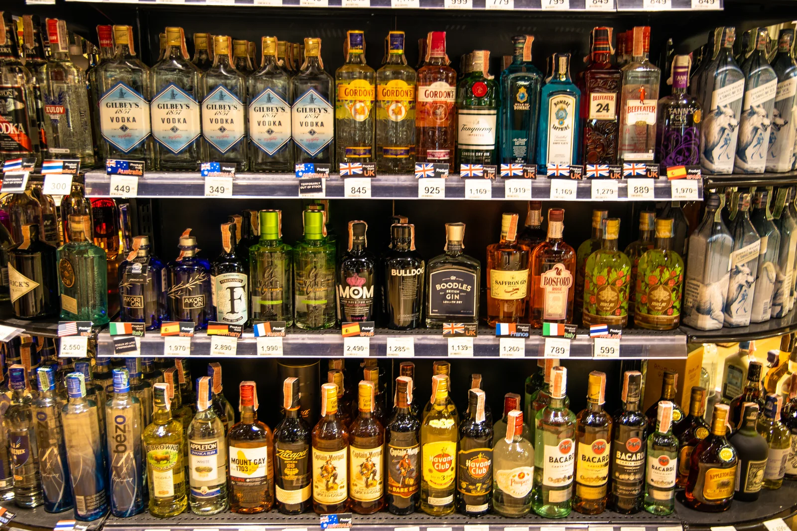 A liquor store owner helping a customer choose a bottle of wine from a well-stocked shelf