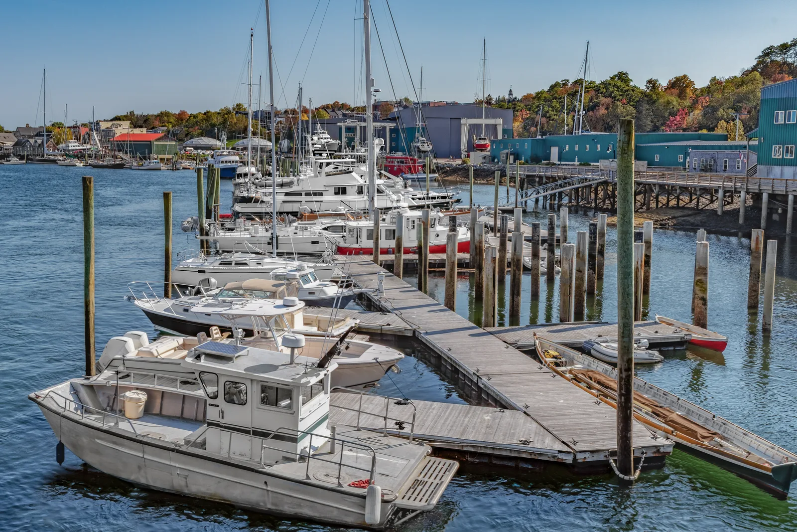 Rows of boats docked in wet slips at a marina with the harbor office and gangway in the background