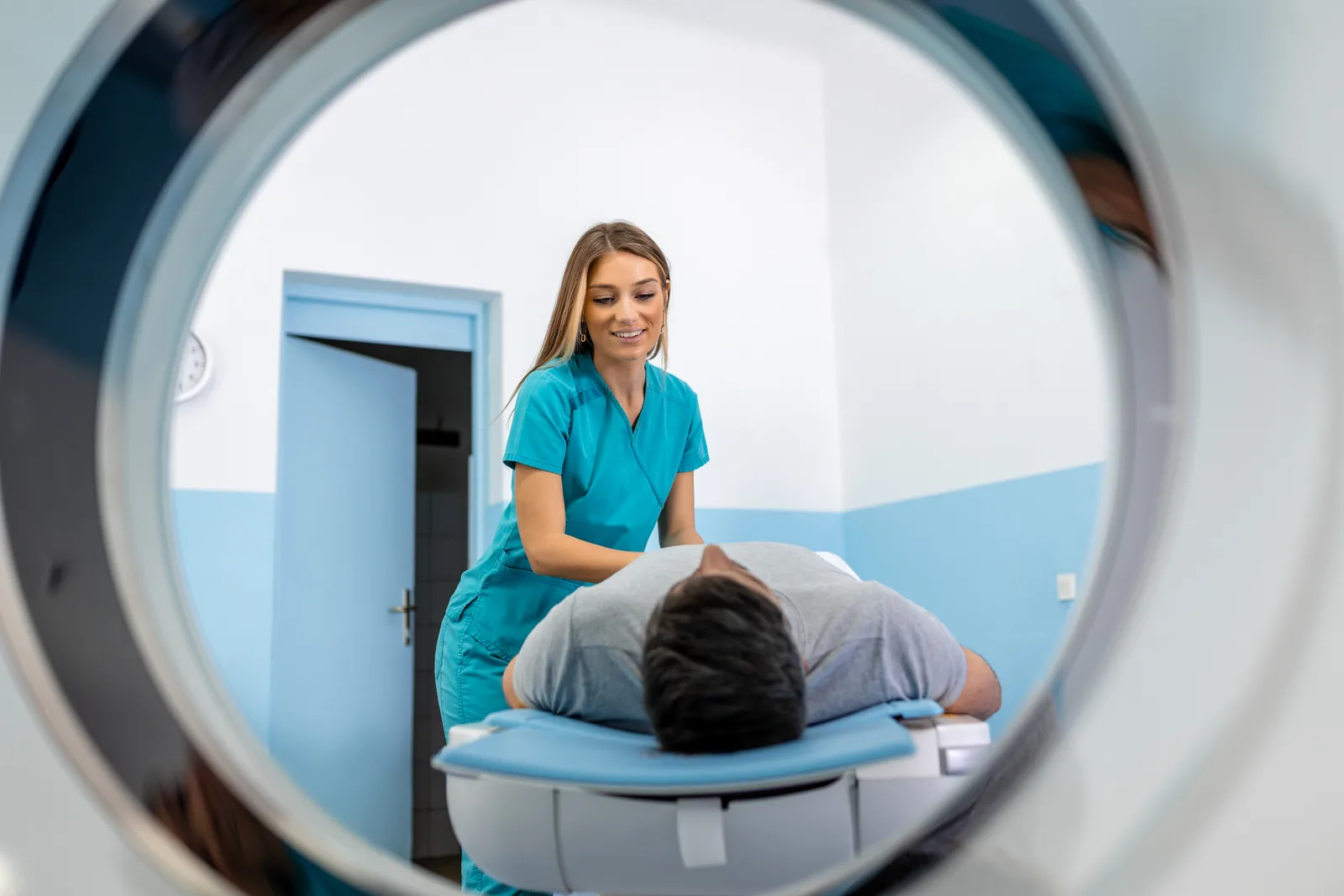 Radiologic technologist preparing a patient for an MRI scan in a modern imaging suite