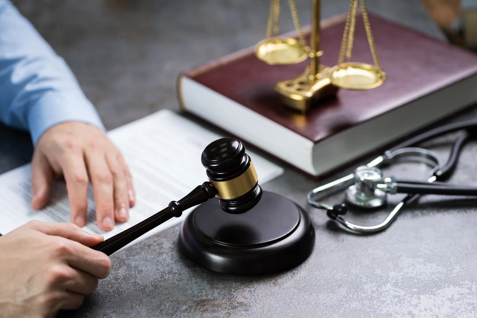 A judge's gavel beside a stethoscope on a malpractice attorney's desk