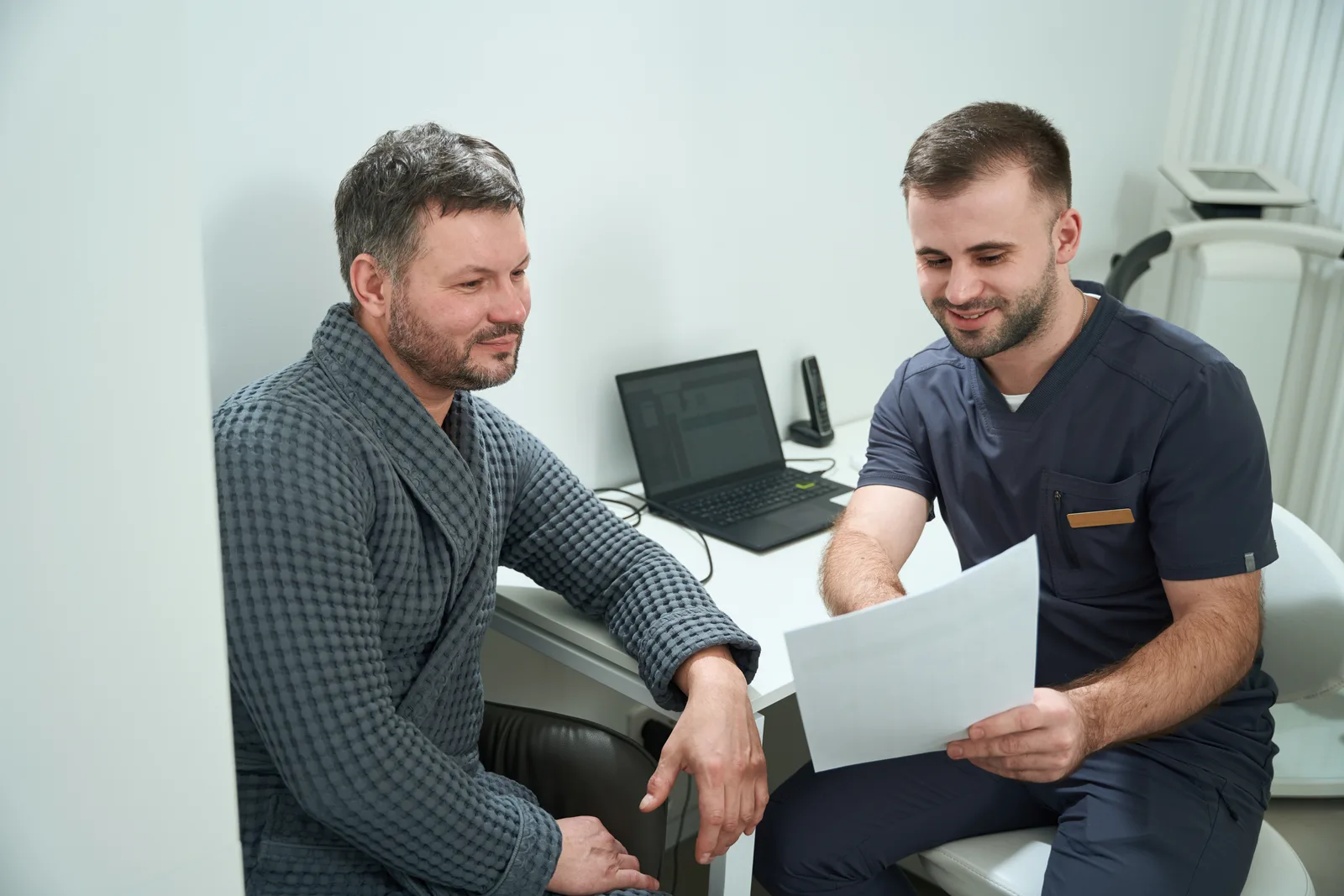 Doctor reviewing lab results and treatment options with a male patient during a private consultation in a men's health clinic