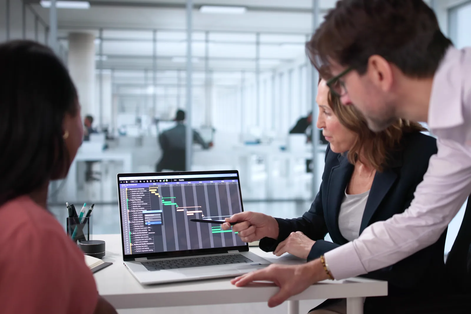 Mid-market SaaS marketing team reviewing a demo pipeline and renewal dashboard together at a laptop in their office