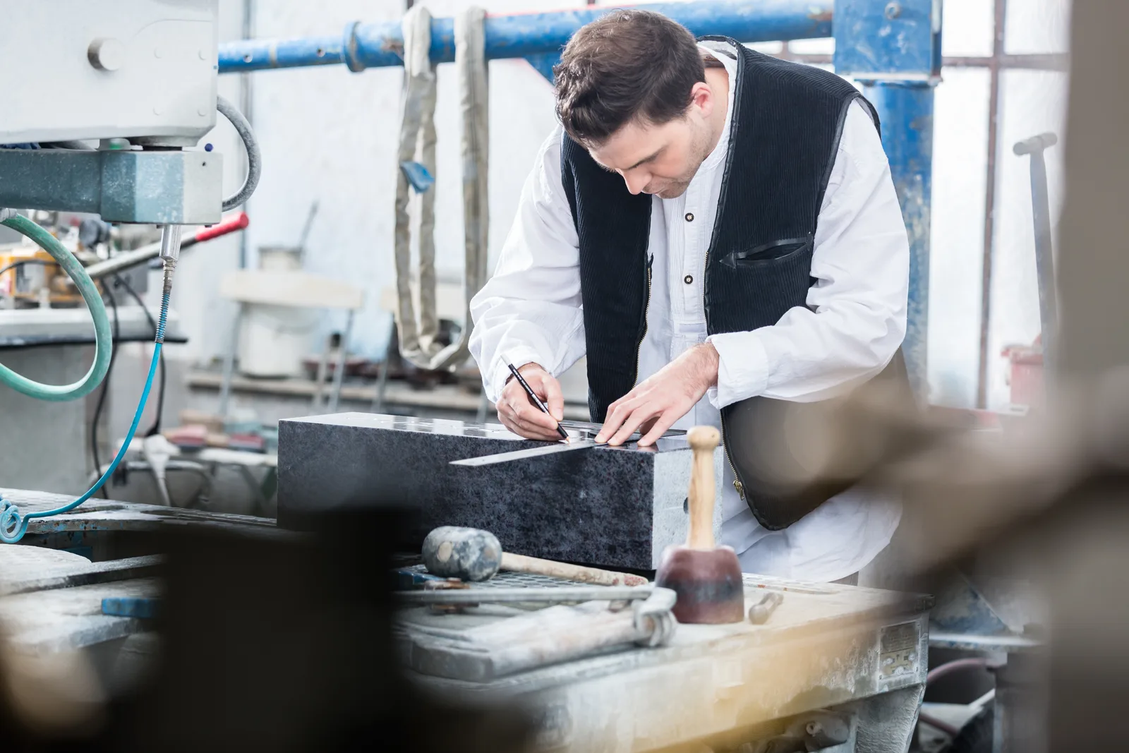 A monument company craftsman hand-finishing engraved lettering on a granite headstone in the workshop