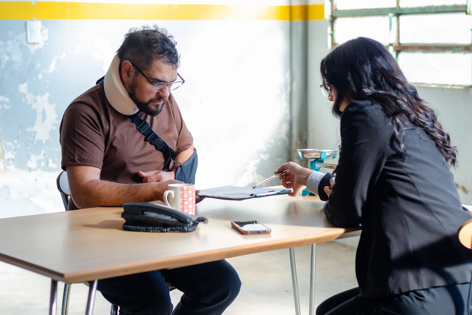 Motorcycle accident attorney reviewing photos of a damaged motorcycle and medical records with an injured rider client at a law office conference table