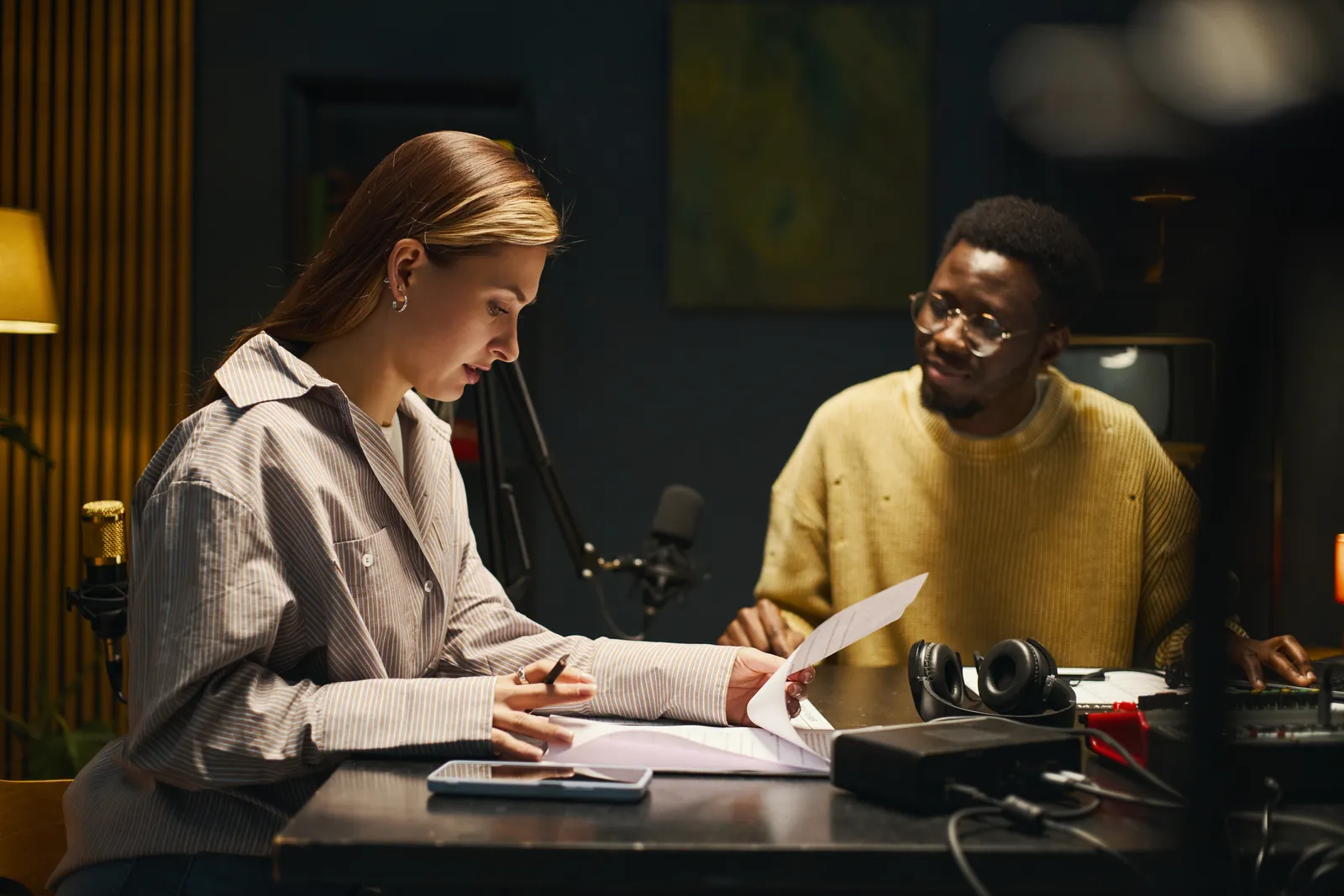 Music lawyer reviewing a recording contract with an independent artist across her office desk