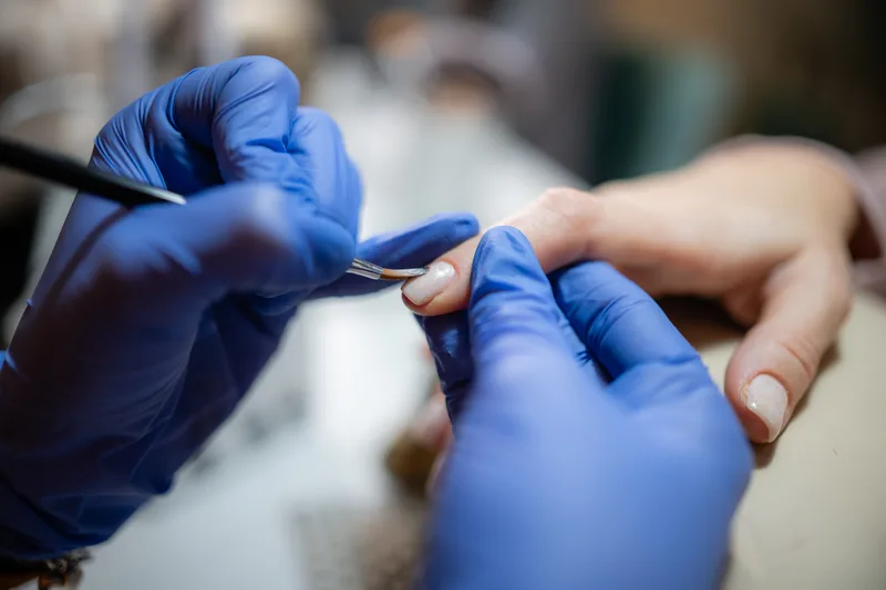 Manicurist applying polish during a manicure at a nail salon