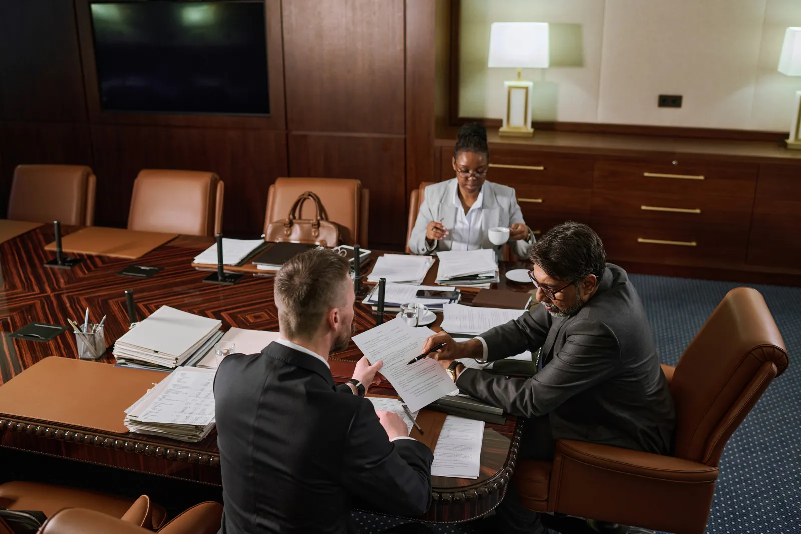 Nonprofit attorney reviewing bylaws and 501(c)(3) paperwork with two founders at a conference table