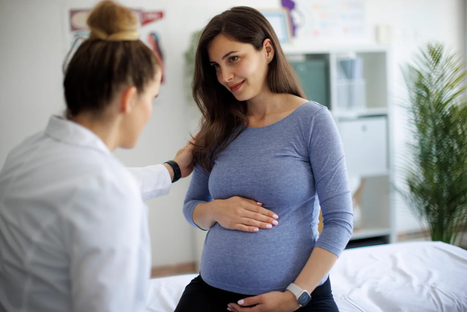 An OB/GYN talks through an ultrasound with a pregnant patient in the exam room