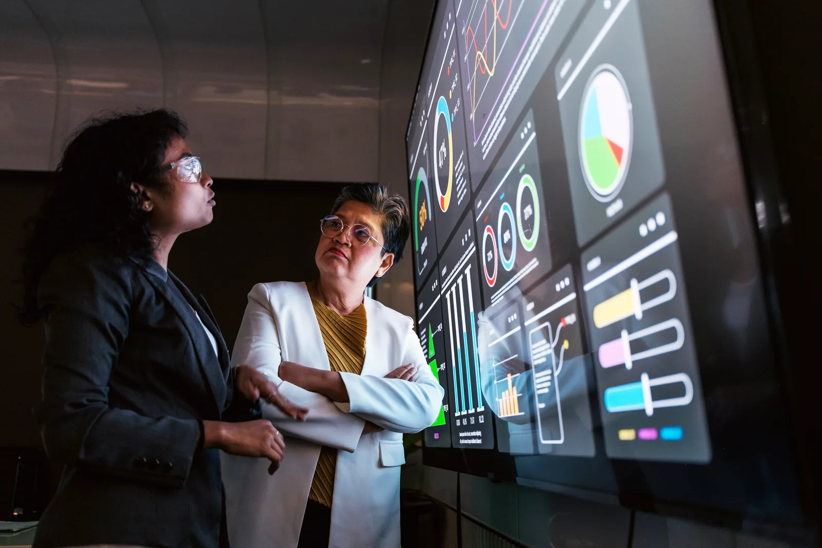 Engineering team reviewing live metrics, logs, and trace dashboards together on a monitor in their office
