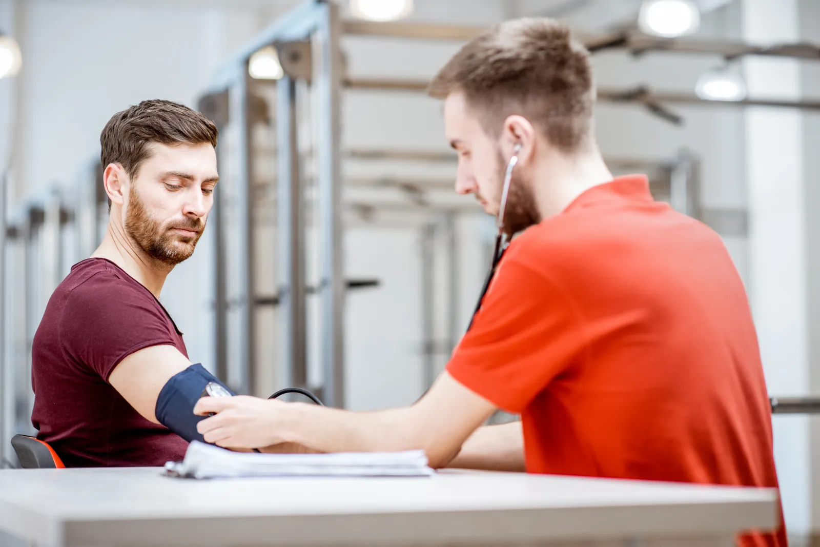 Occupational health nurse checking a warehouse worker's blood pressure during a pre-employment physical exam