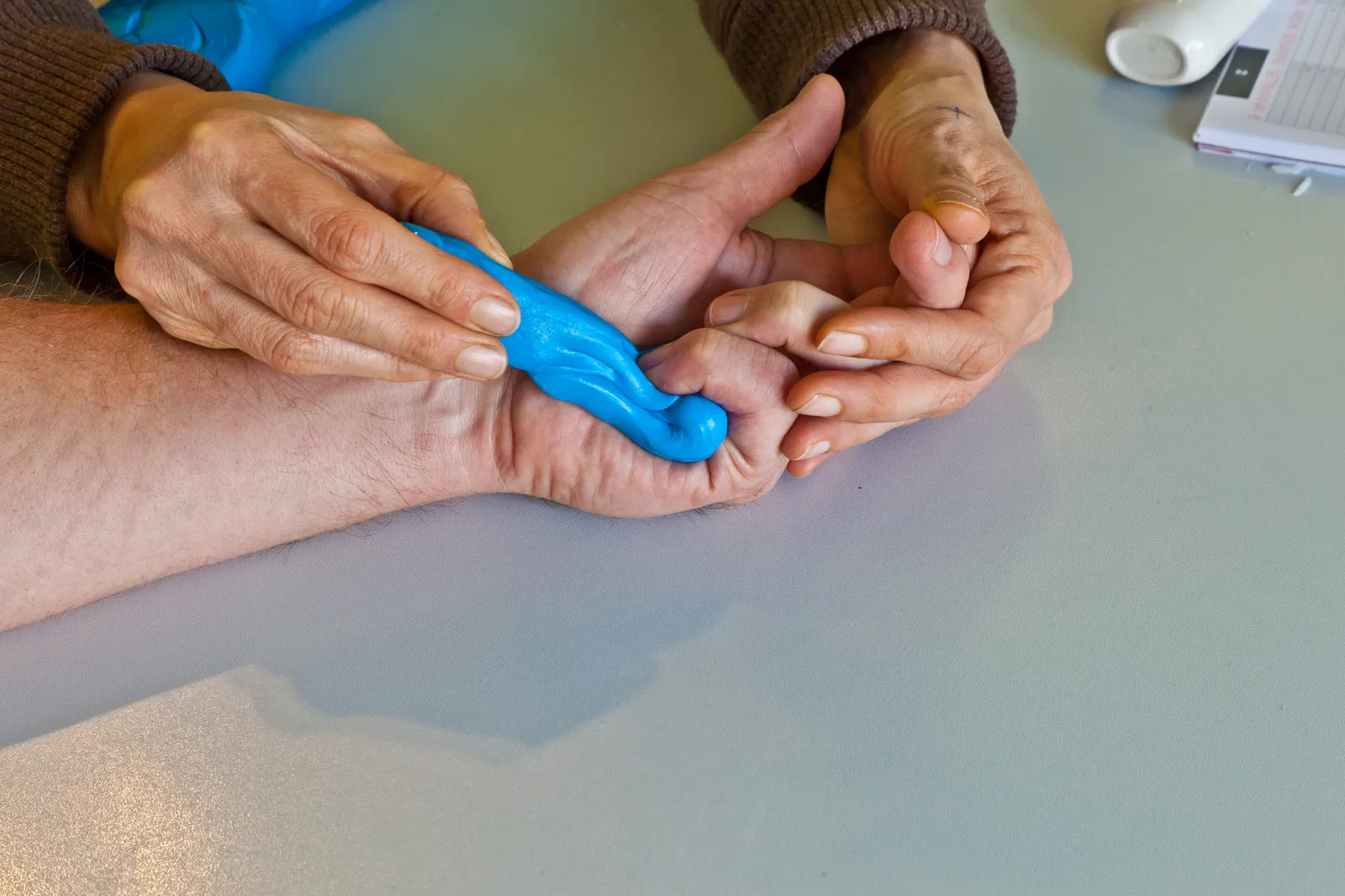 Occupational therapist guiding a patient through hand exercises with therapy putty