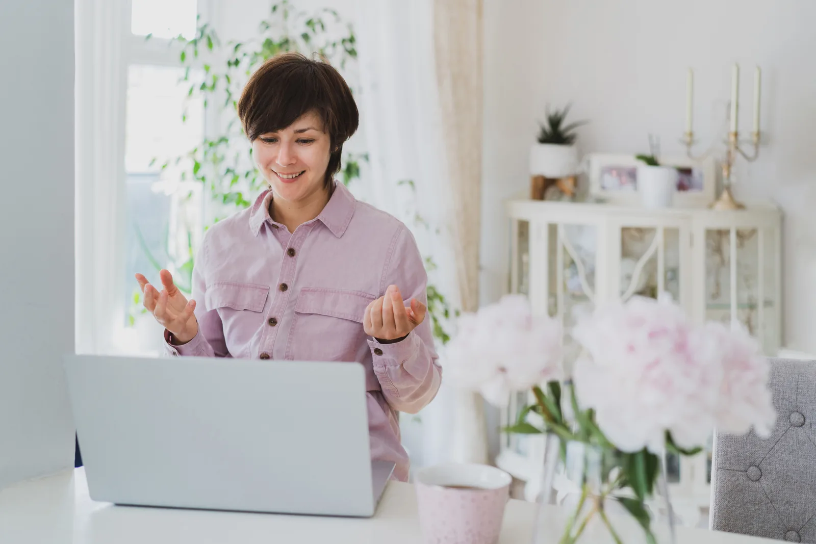 Online life coach leading a video coaching call with a client from a laptop in a bright home office