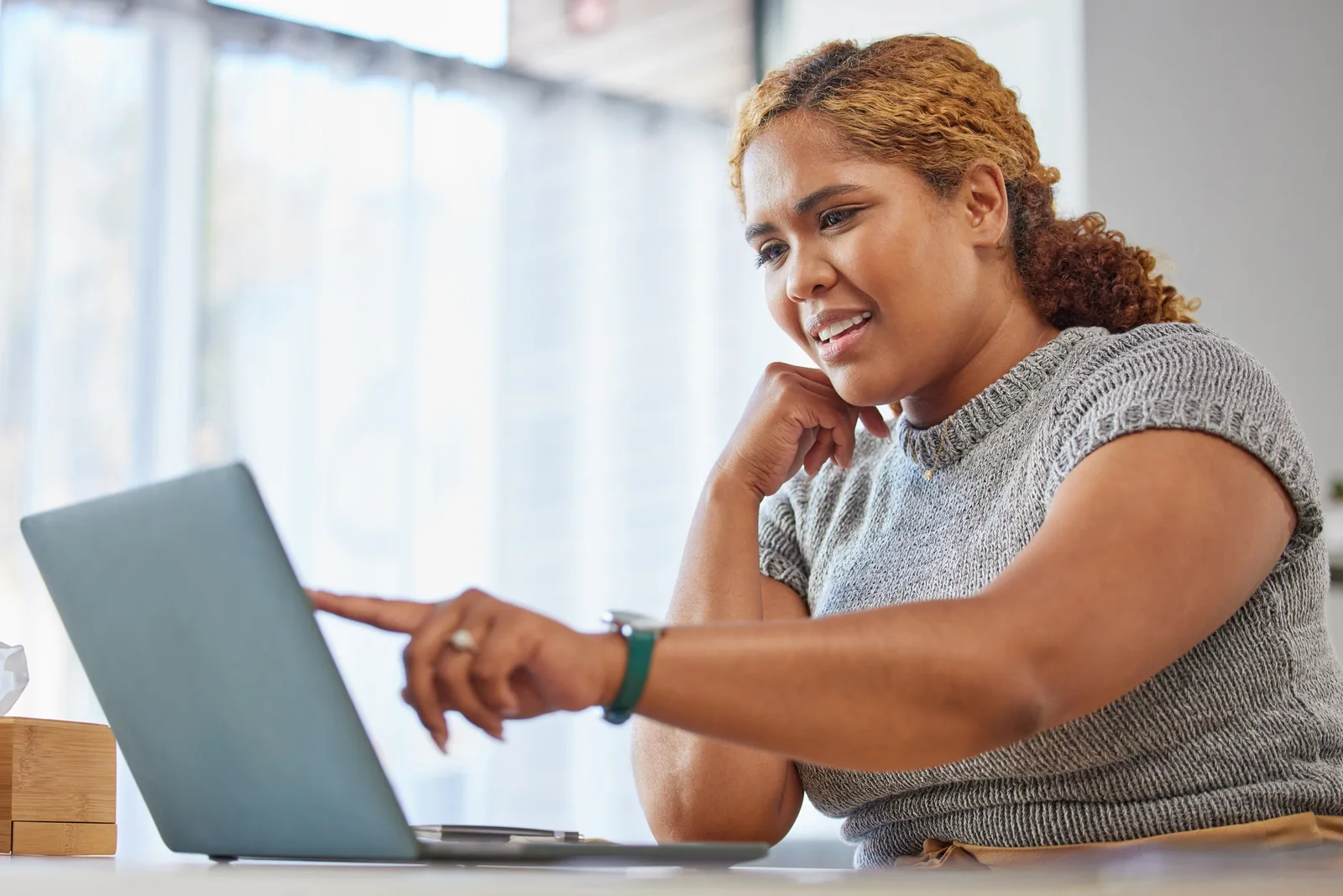 Community manager reviewing member activity and discussion threads on a laptop in a home office