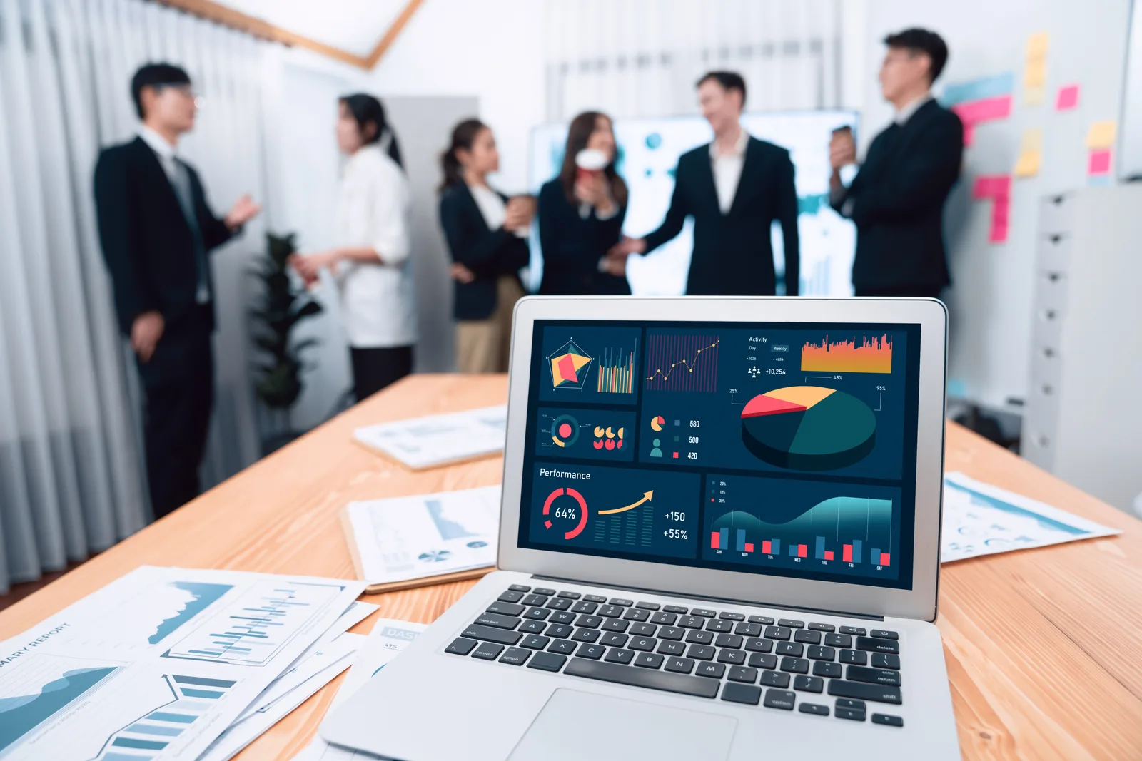 Online course platform software product team reviewing creator trial and course-completion dashboards together on a laptop in their office