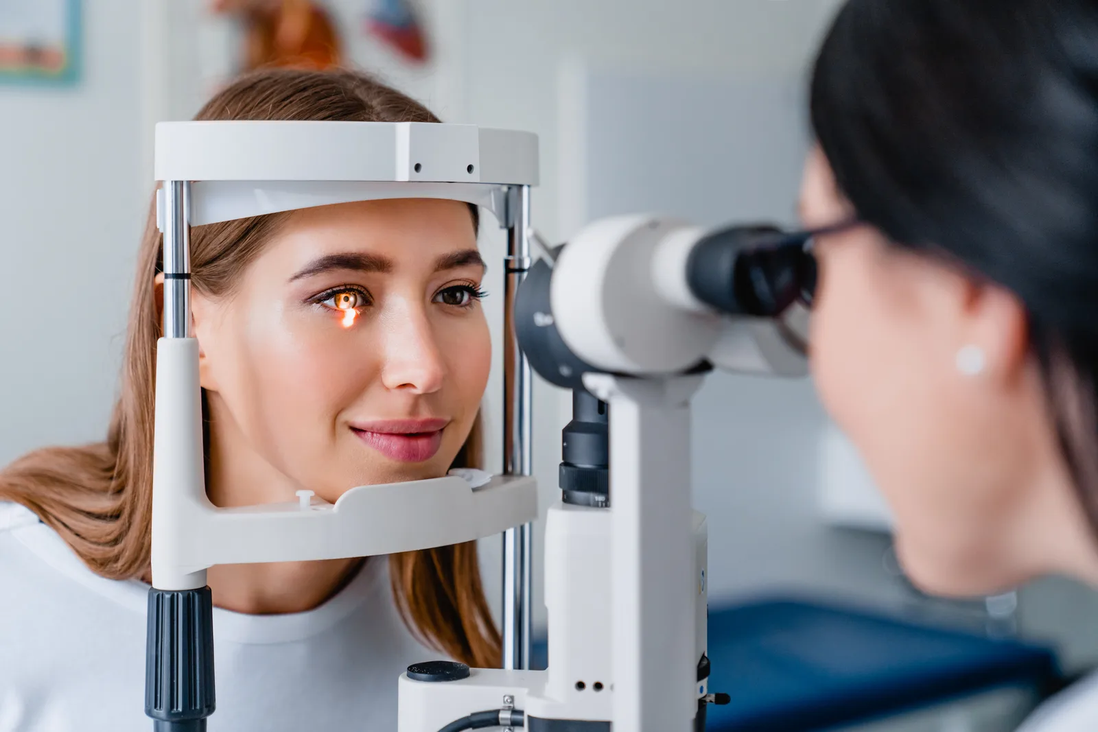 Optometrist positioning a phoropter in front of a patient in the exam chair