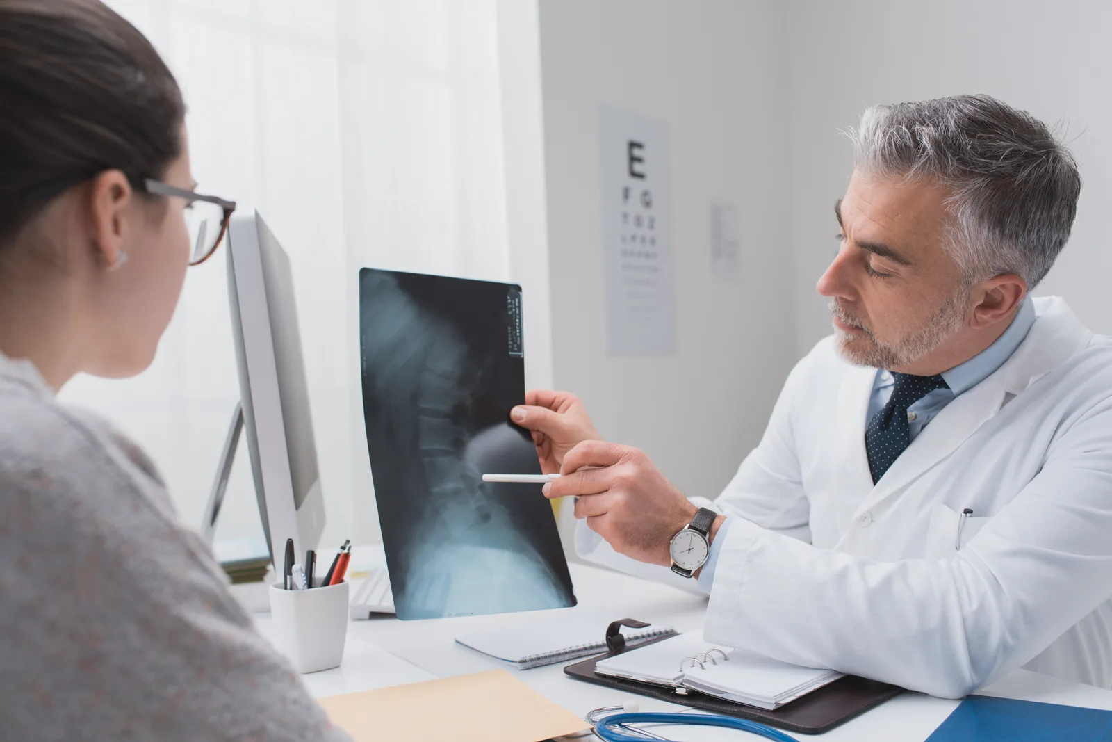 Pain management physician reviewing a spine scan with a patient during a consultation