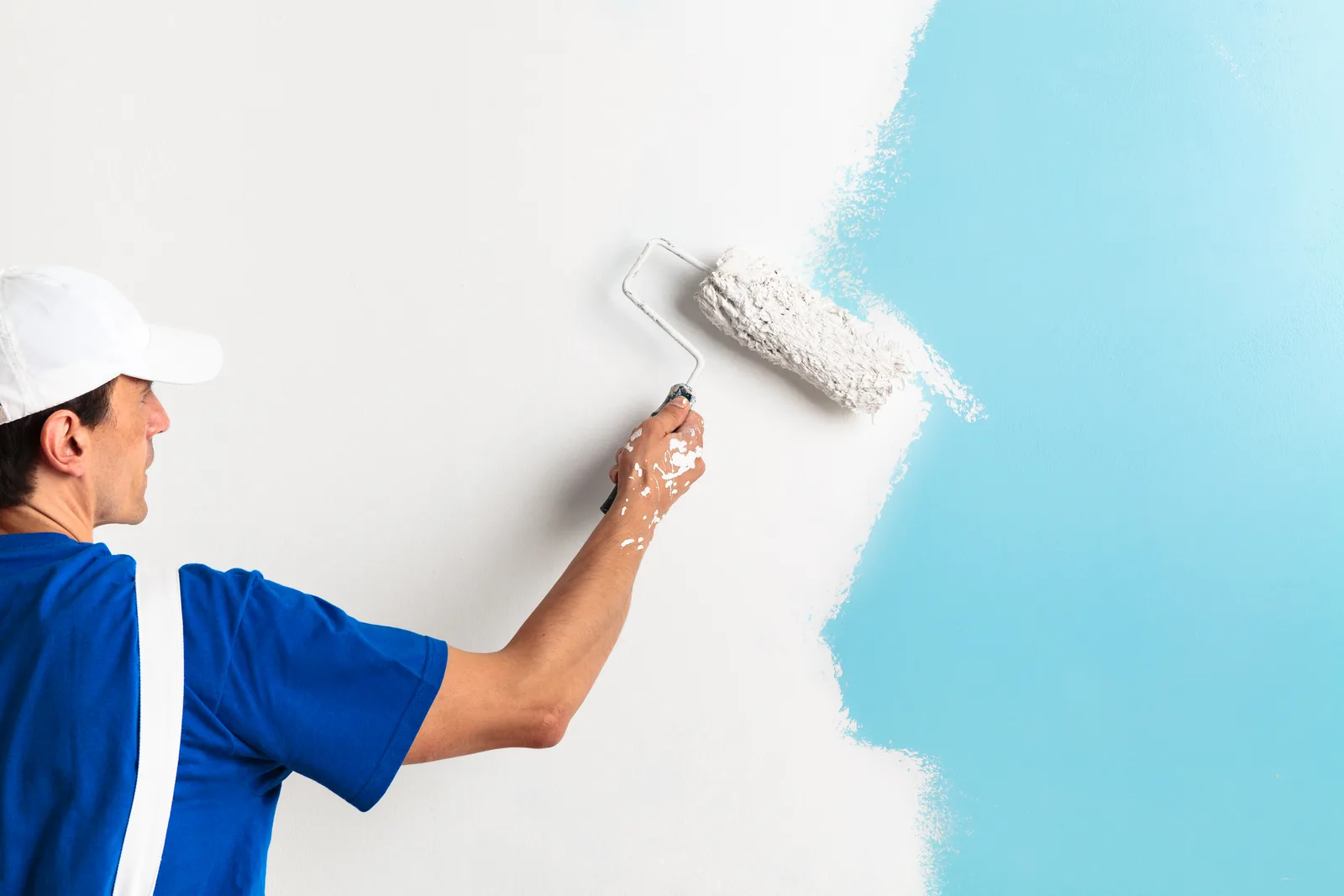 Painter rolling fresh paint onto a living room wall during an interior repaint