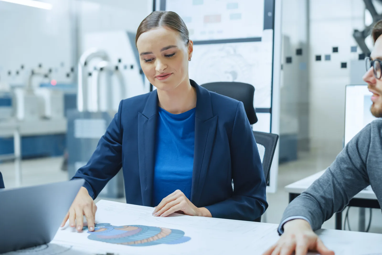 Patent attorney reviewing a mechanical diagram and draft patent application with an inventor at a conference table