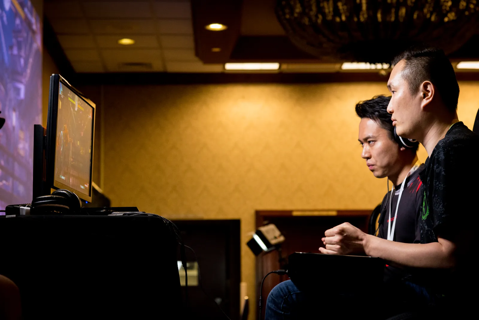 Two game developers playtesting a build side by side at their studio workstations